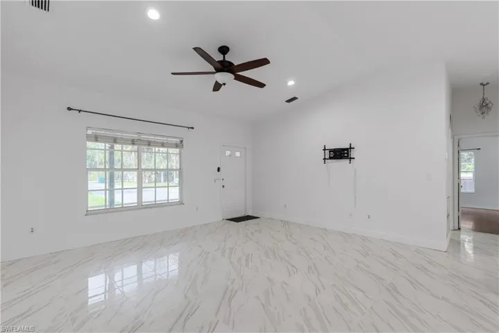 Unfurnished room featuring a wealth of natural light, vaulted ceiling, and ceiling fan