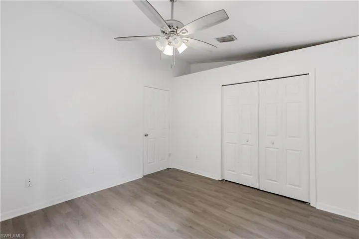 Unfurnished bedroom featuring ceiling fan, hardwood / wood-style flooring, lofted ceiling, and a closet