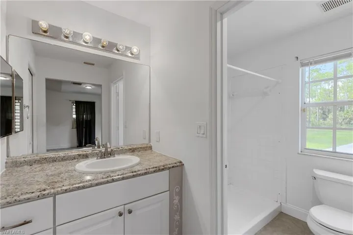 Bathroom featuring vanity, a shower, toilet, and tile patterned floors