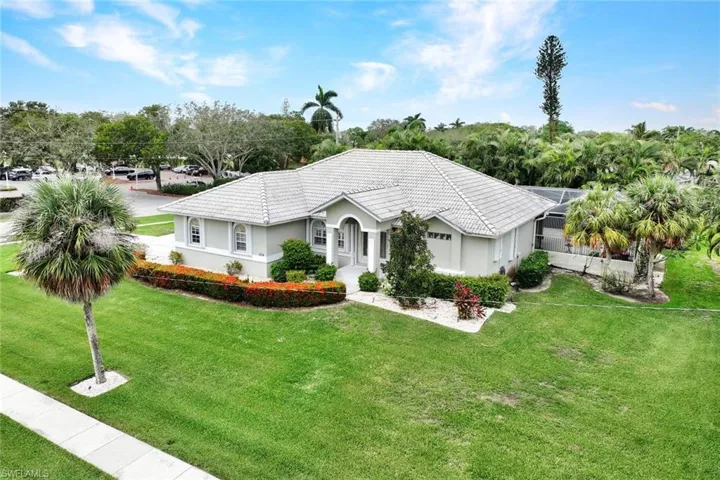 Ranch-style home featuring a front yard, a garage, and a lanai