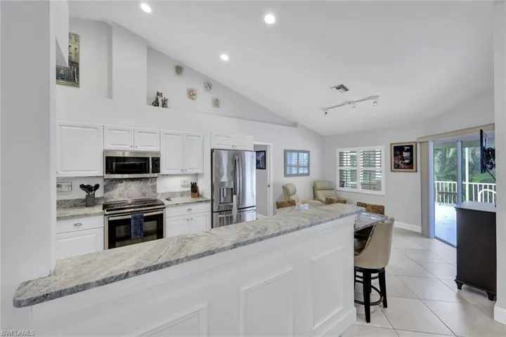 Kitchen featuring white cabinets, a breakfast bar, light stone counters, and stainless steel appliances