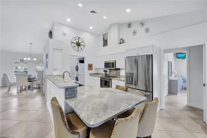 Kitchen featuring kitchen peninsula, appliances with stainless steel finishes, light stone counters, pendant lighting, and a breakfast bar area
