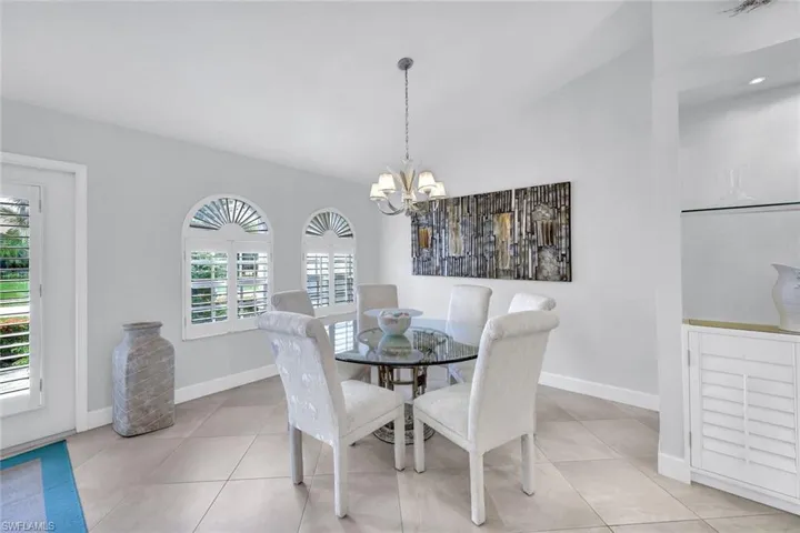 Tiled dining room with plenty of natural light, lofted ceiling, and a notable chandelier