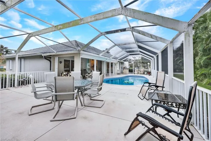 View of swimming pool with glass enclosure and a patio