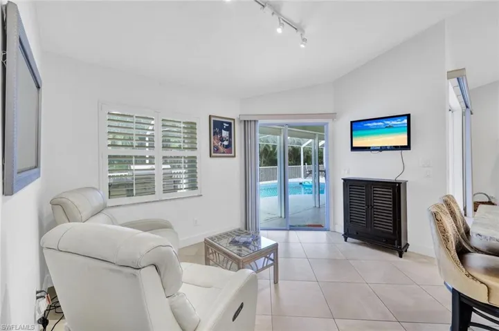 Living room featuring plenty of natural light, light tile patterned floors, and lofted ceiling