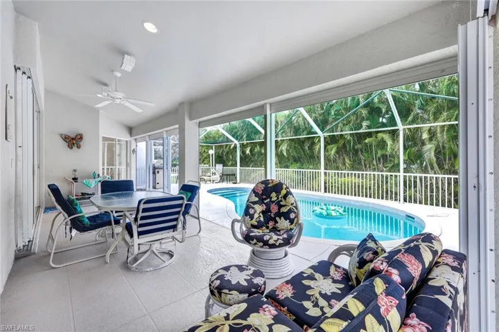 View of pool featuring a patio area, ceiling fan, and glass enclosure