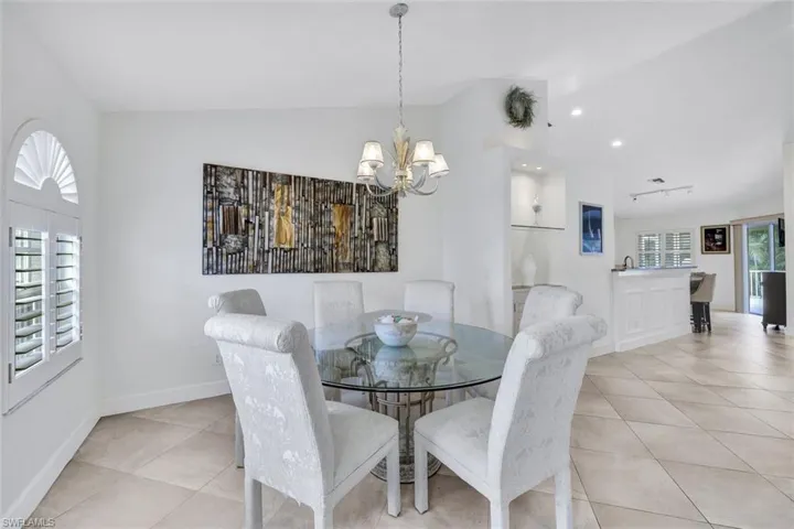Dining space featuring a chandelier, vaulted ceiling, and light tile patterned flooring