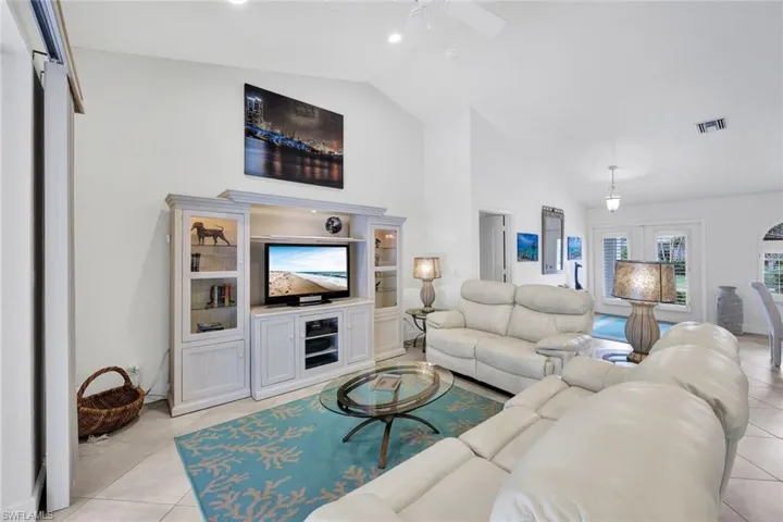 Living room with ceiling fan, light tile patterned flooring, french doors, and vaulted ceiling