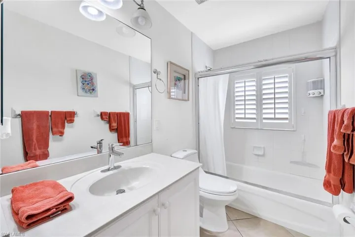 Full bathroom with tile patterned floors, toilet, vanity, and tiled shower / bath