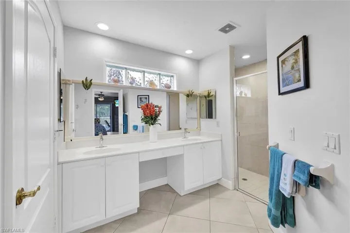 Bathroom with tile patterned flooring, vanity, ceiling fan, and a shower with door
