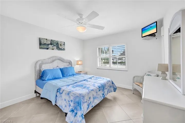 Tiled bedroom featuring ceiling fan and a closet