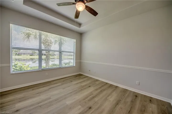 Unfurnished room featuring ceiling fan, a raised ceiling, a wealth of natural light, and light hardwood / wood-style floors
