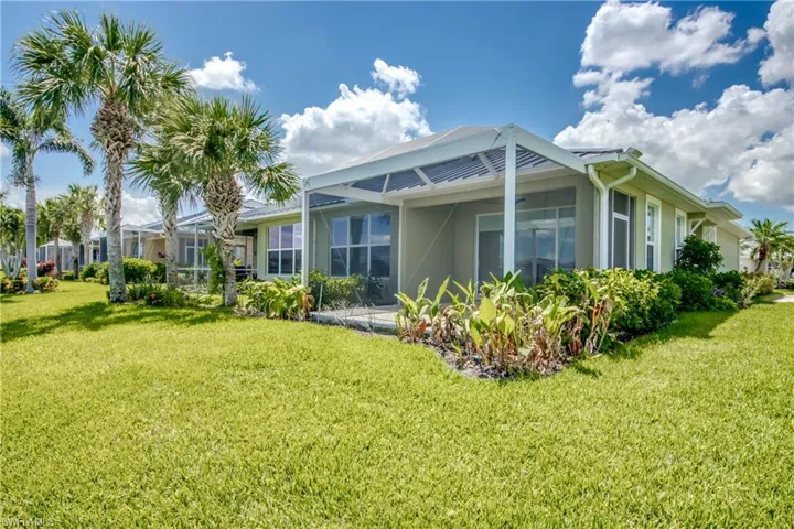 View of side of home featuring a lawn and a lanai
