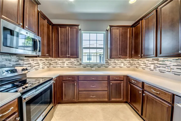 Kitchen featuring appliances with stainless steel finishes, light tile patterned floors, and tasteful backsplash