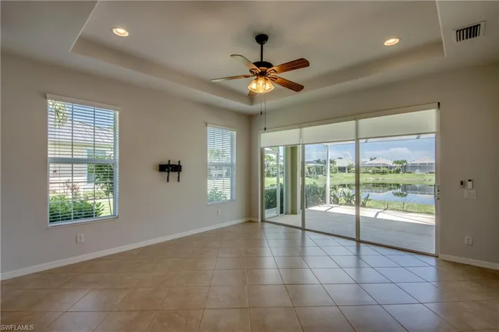 Tiled spare room featuring ceiling fan, a water view, and a tray ceiling
