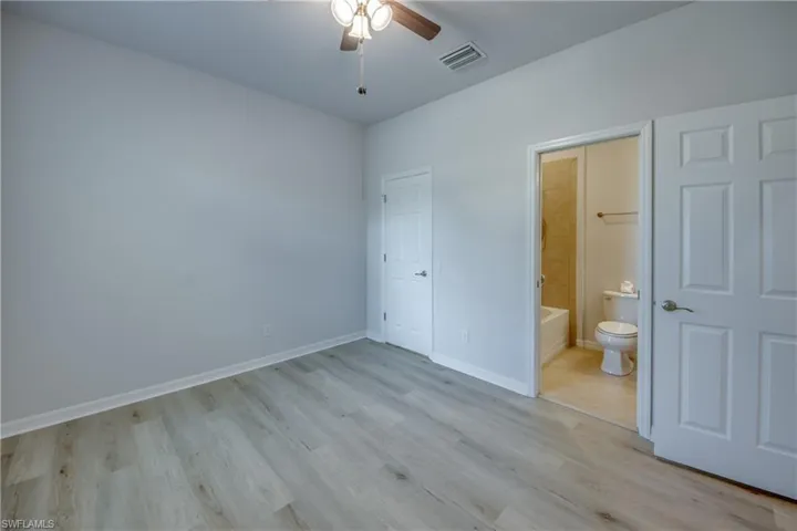 Unfurnished bedroom with ceiling fan, connected bathroom, and light hardwood / wood-style floors