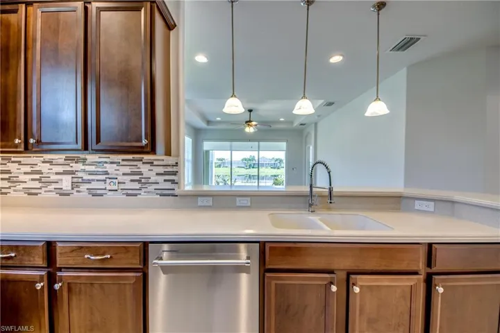 Kitchen with decorative backsplash, ceiling fan, sink, stainless steel dishwasher, and decorative light fixtures