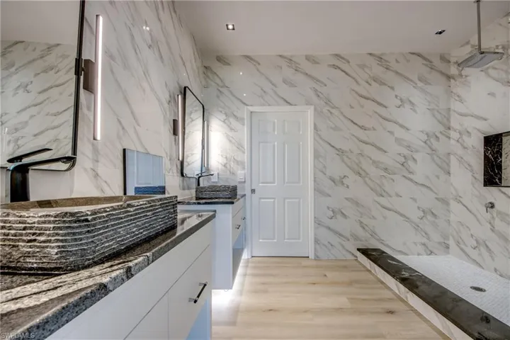 Kitchen with tile walls, white cabinets, and light hardwood / wood-style floors