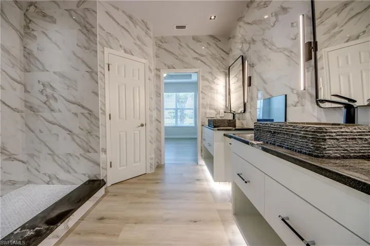 Bathroom featuring tasteful backsplash, vanity, tile walls, and wood-type flooring