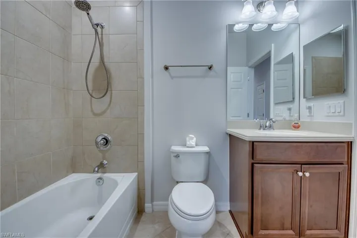 Full bathroom featuring tiled shower / bath combo, tile patterned floors, vanity, and toilet