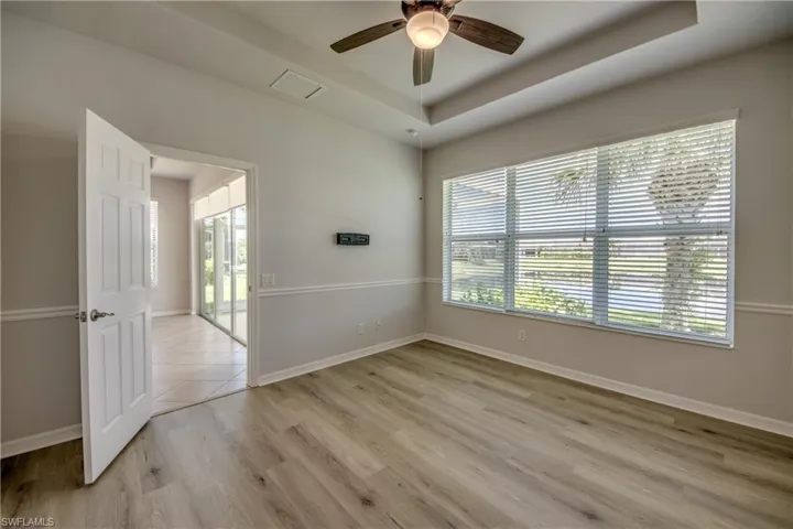 Unfurnished room featuring a raised ceiling, ceiling fan, and light hardwood / wood-style floors