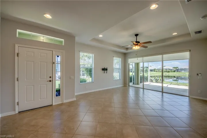 Tiled foyer entrance featuring ceiling fan and a raised ceiling