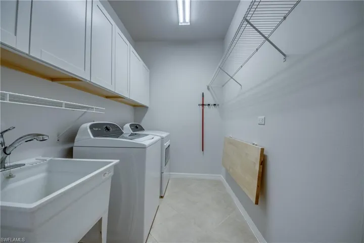 Laundry area with cabinets, light tile patterned floors, sink, and washer and clothes dryer