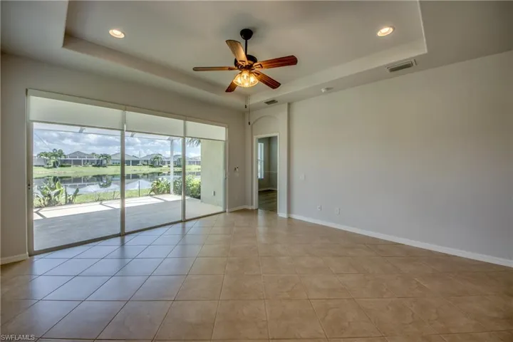 Unfurnished room with ceiling fan, light tile patterned floors, and a tray ceiling