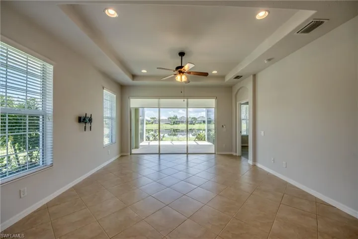 Tiled spare room featuring a tray ceiling, plenty of natural light, and ceiling fan