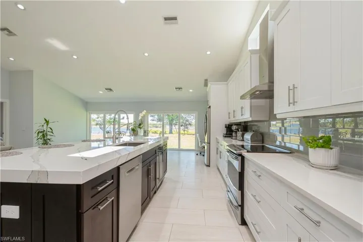Kitchen with white cabinetry, stainless steel appliances, recessed lighting, a spacious island, and tasteful backsplash