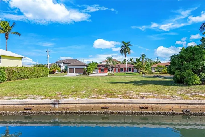 Rear view of house featuring a water view, a lawn, and an attached garage