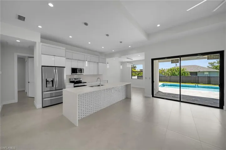 Kitchen with stainless steel appliances, modern cabinets, white cabinetry, light countertops, and recessed lighting
