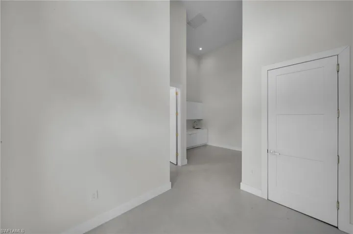 Corridor featuring baseboards and finished concrete flooring