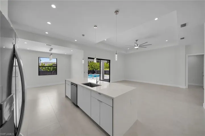 Kitchen featuring fridge, modern cabinets, open floor plan, dishwasher, and a tray ceiling