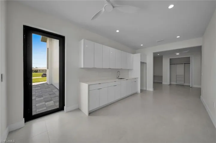 Kitchen with modern cabinets, a ceiling fan, white cabinets, light countertops, and recessed lighting