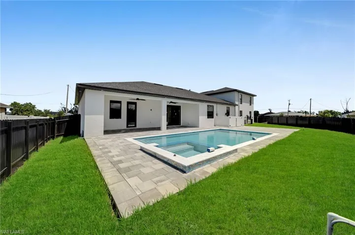Rear view of house with a fenced backyard, ceiling fan, stucco siding, and a patio area
