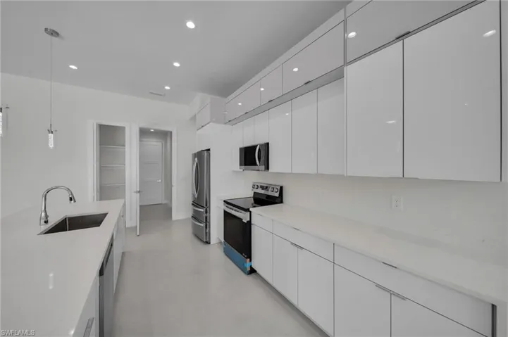 Kitchen with stainless steel appliances, modern cabinets, white cabinetry, concrete floors, and recessed lighting