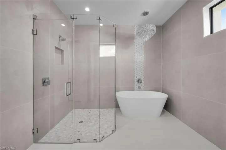 Full bathroom with a shower stall, tile walls, a freestanding tub, and tile patterned floors