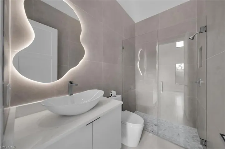 Bathroom featuring tile walls, a shower stall, vanity, and tile patterned floors