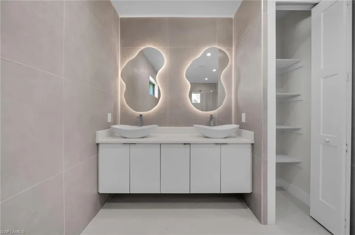 Full bathroom featuring double vanity and tile walls
