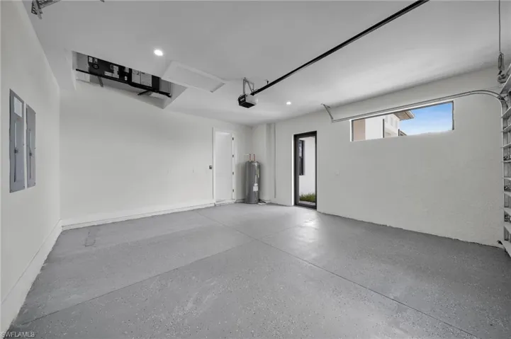 Garage with electric water heater, a garage door opener, and recessed lighting
