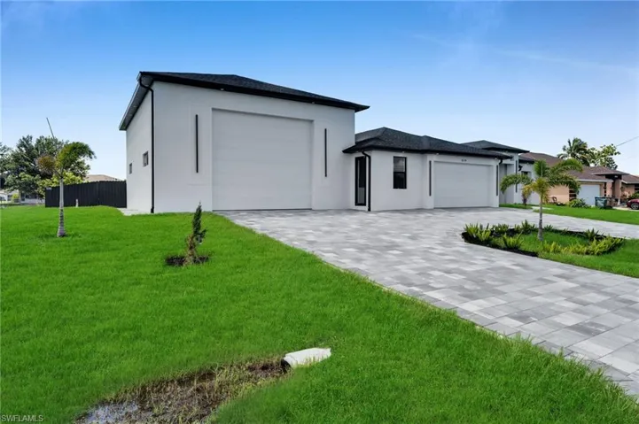 View of front of home with an attached garage, stucco siding, and decorative driveway