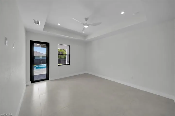 Spare room featuring a raised ceiling, a ceiling fan, a smoke detector, and recessed lighting