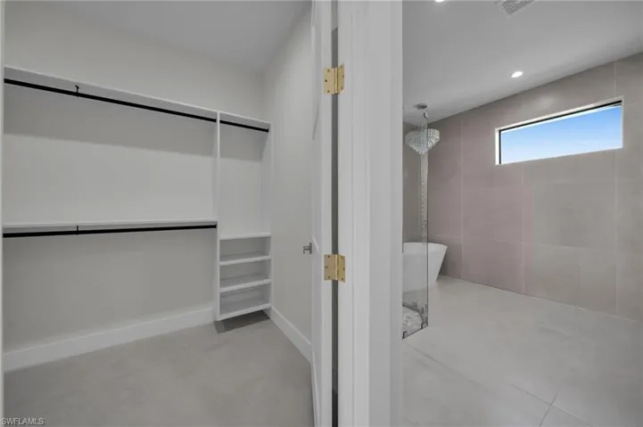 Bathroom featuring tiled shower, a soaking tub, concrete flooring, a walk in closet, and recessed lighting