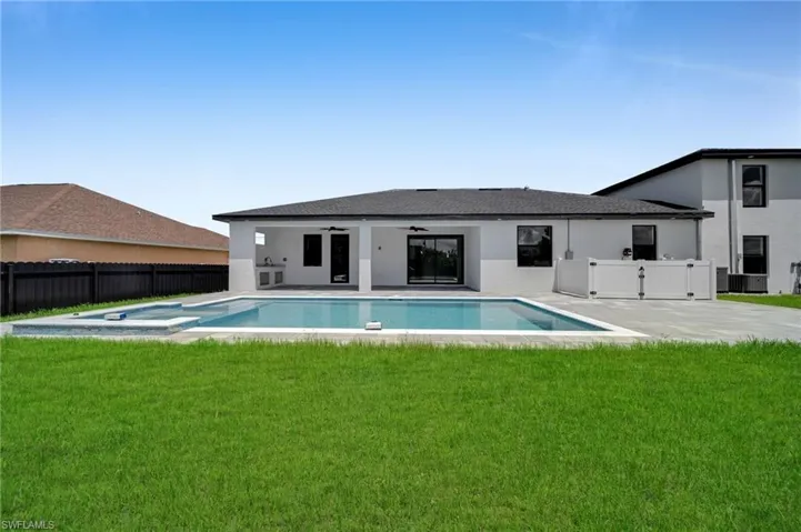 Rear view of house featuring ceiling fan, a patio area, stucco siding, and a pool with connected hot tub