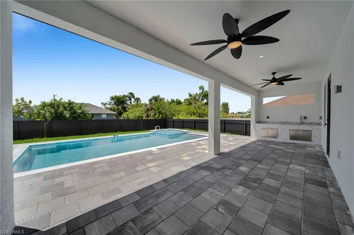 View of swimming pool featuring area for grilling, ceiling fan, a fenced backyard, and a patio area