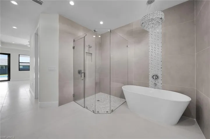 Full bathroom with a shower stall, a freestanding tub, recessed lighting, tile patterned floors, and a chandelier