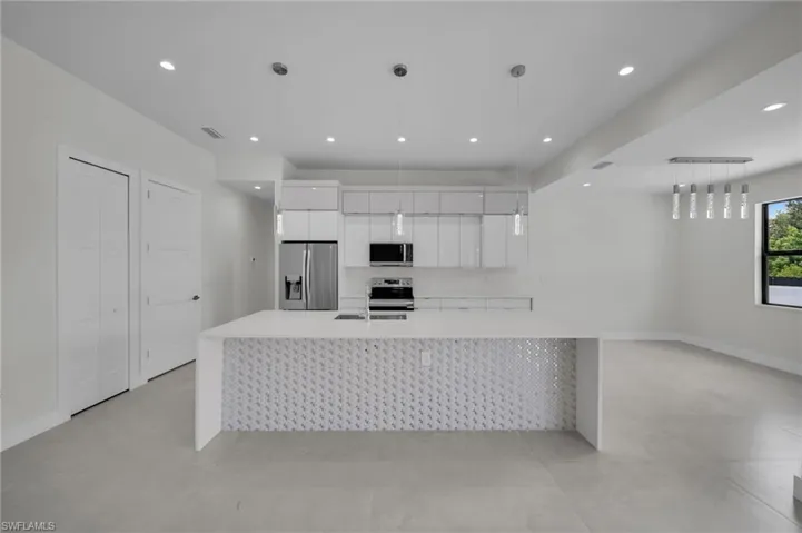 Kitchen featuring stainless steel appliances, white cabinetry, modern cabinets, light countertops, and a large island