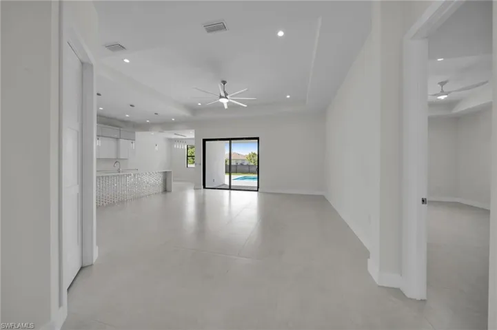 Unfurnished living room featuring a ceiling fan, a raised ceiling, and recessed lighting