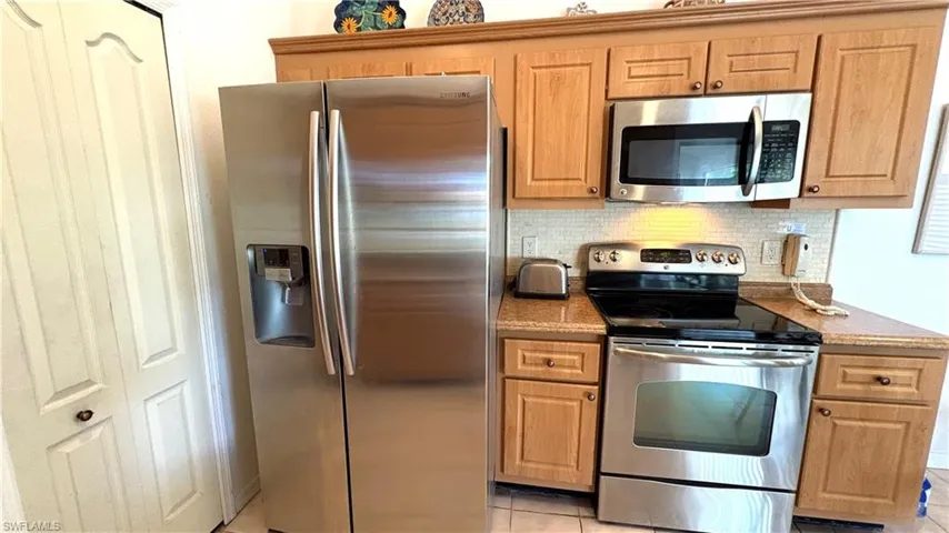 Eat-in Kitchen features NEWER stainless steel appliances, decorative backsplash, light tile patterned floors, granite counters, and stacking washer & dryer.